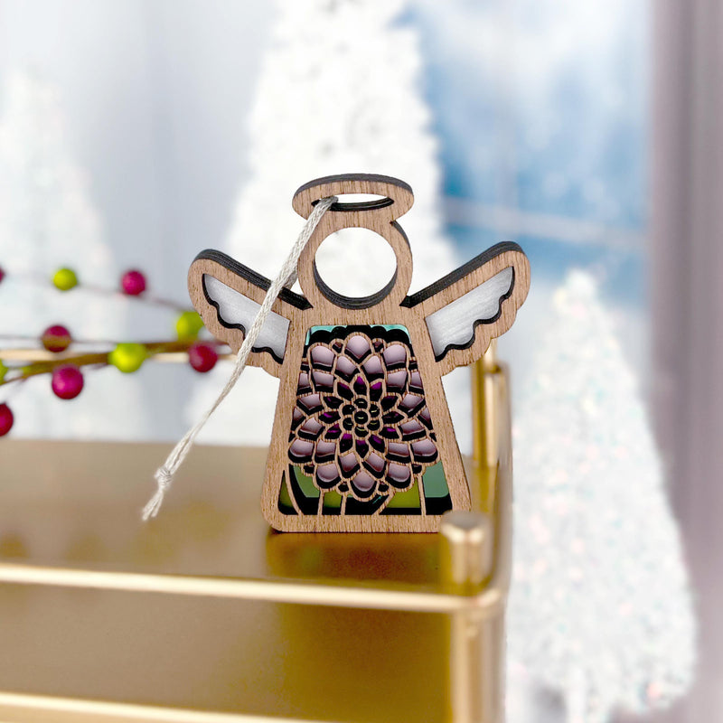 The Forged Flare® Chrysanthemum Ornament with Imperfections is a 3.5" handcrafted Mother's Angels® wooden angel figurine featuring a cut-out flower design, displayed on gold with blurred white trees and red berries in the background.
