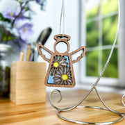 The Warehouse Return - Daisy Ornament (3.5" H) by Forged Flare®, from the Mother's Angels® collection, features cutout wings, two daisies, and a blue background—perfectly displayed on a metal stand for the Amazon marketplace.