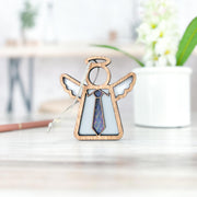 The Forged Flare® Forever Your Father Ornament is a 3.5" Mother’s Angels® figurine with a patterned tie, displayed on a light surface with a white flower pot and blurred pencil in the background—an ideal Father's Day gift.
