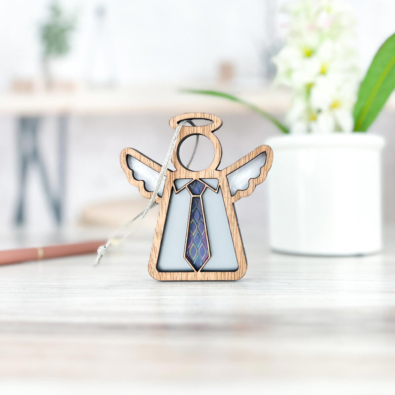 The Forged Flare® Forever Your Father Ornament is a 3.5" Mother’s Angels® figurine with a patterned tie, displayed on a light surface with a white flower pot and blurred pencil in the background—an ideal Father's Day gift.