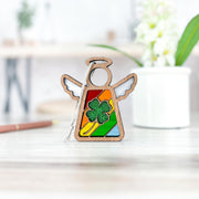 The Glittery Four-Leaf Clover Ornament from Forged Flare®, part of the Mother's Angels® collection, is a charming 3.5" wooden angel figurine. It features a rainbow-colored stained glass design with a glittery green four-leaf clover in the center. Resting on a light wood surface alongside a potted plant and pencil with a blurred background, this piece makes for ideal St. Patrick's Day decor.
