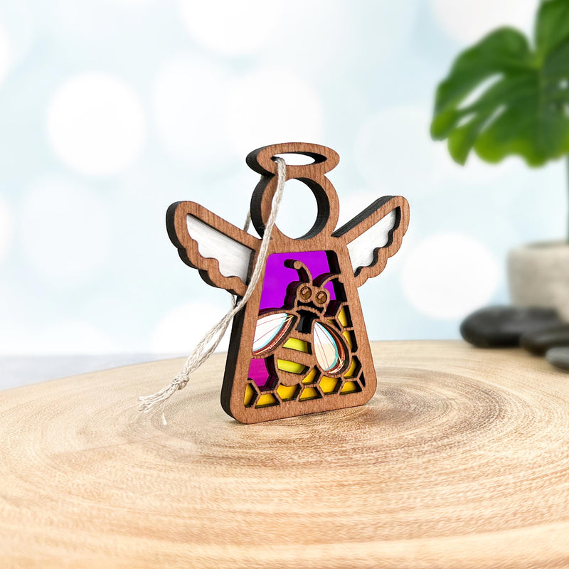 The Forged Flare® Warehouse Return - Honey Bee Ornament is a 3.5" Mother's Angels® wooden angel figurine with a string, featuring a purple and yellow stained glass-style bee—perfect for Amazon marketplace listings.