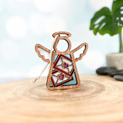 The Forged Flare® Letters of Love Ornament is a 3.5" Mother's Angels® wooden angel figurine with colorful envelopes and hearts, perfect as a Christmas tree ornament or mail carrier gift, displayed on wood with bokeh lights in the background.
