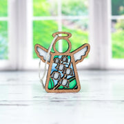 The Forged Flare® Lily of the Valley Ornament | 3.5" Angel Figurine from Mother's Angels® features white wings and blue and white floral designs, displayed on a white surface before windows overlooking a lush garden.