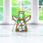 The Magnolia Ornament by Forged Flare® is a 3.5" Mother's Angels® figurine, featuring white wings, a magnolia flower center, and a hanging string—ideal for your Christmas tree or as a unique decor piece.