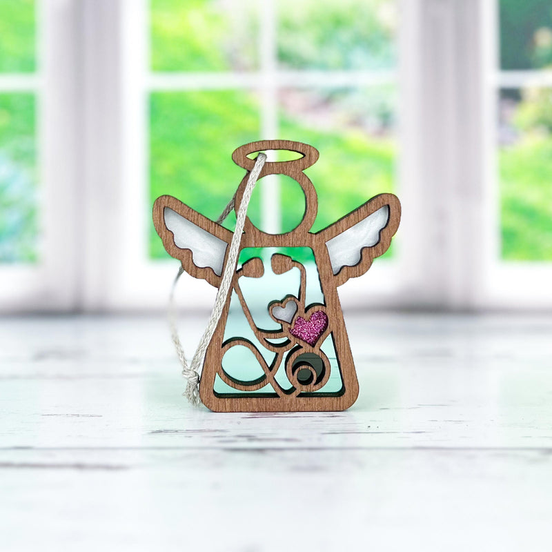 The Forged Flare® Mother's Angels® 3.5" Doctor/Nurse Ornament with Imperfections features a wooden angel with a stethoscope and pink glitter heart—an ideal medical-themed centerpiece for any space.