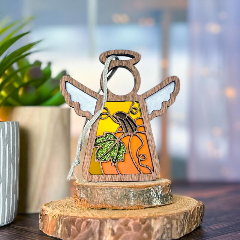 The Forged Flare® Festive Pumpkin Ornament is a 3.5"H Mother's Angels® figurine featuring stained glass-style wings and pumpkin-leaf detail, perfect for adding Thanksgiving charm to your indoor decor.