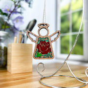 The Forged Flare® Red Rose Ornament with Imperfections is a 3.5" Mother's Angels® figurine, featuring a stained-glass-effect red rose center and hanging on a silver stand—perfect for display on your desk or near a window.