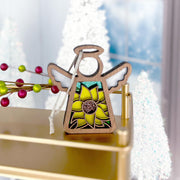 The Forged Flare® Warehouse Return - Sunflower Ornament is a 3.5" Mother's Angels® figurine featuring a stained glass-style yellow flower, gold shelf, and snowy trees with red berries and frosted windows in the background.