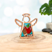 The Forged Flare® Mother's Angels® Teacher Ornament with Imperfections is a 3.5" handcrafted wooden angel figurine with wings and an apple motif, perfect as a teacher-themed centerpiece on any smooth surface.