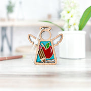 Handcrafted by Forged Flare®, this 3.5" Teacher Ornament with Imperfections is a Mother's Angels® angel figurine featuring stained-glass details—a red apple and two pencils—making it a charming teacher-themed centerpiece for any space.