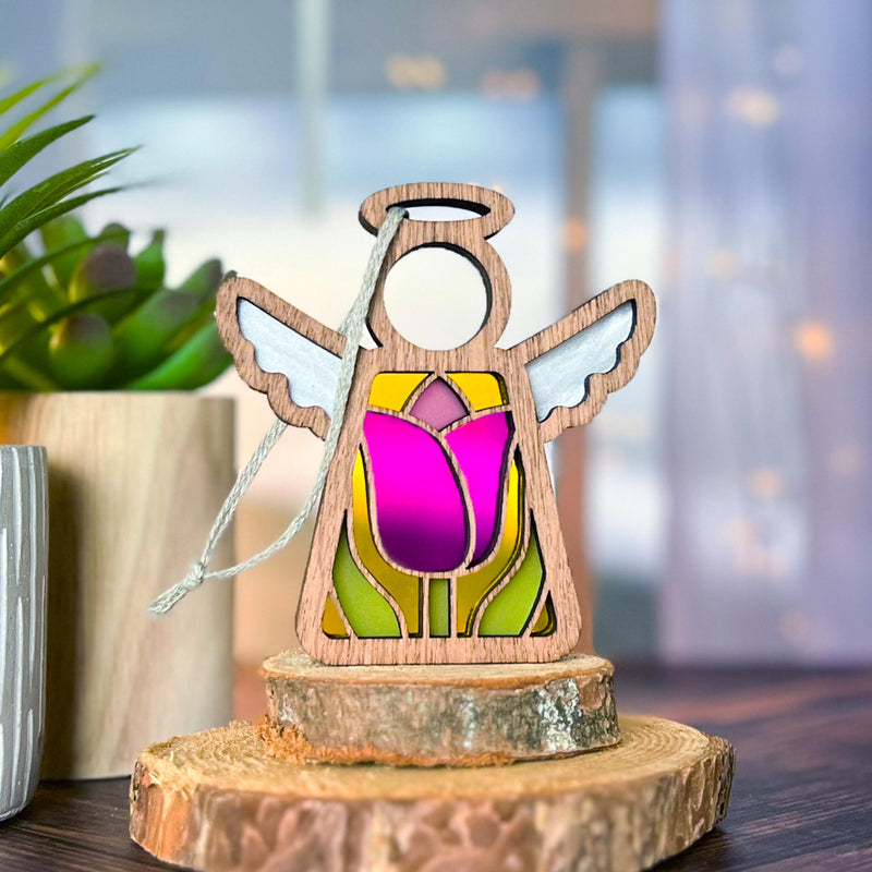 The Forged Flare® Tulip Ornament | 3.5" (H) Angel Figurine from Mother's Angels® features stained glass with a pink tulip, white wings, and a hanging string—perfect for heartfelt decor or a meaningful gift symbolizing love and renewal.