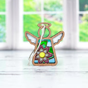 The Forged Flare® Mother's Angels® Water Lily Ornament is a 3.5" stained glass angel figurine with a wooden frame and white string, featuring colorful sections and a central water lily design, displayed by a window with green views outside.