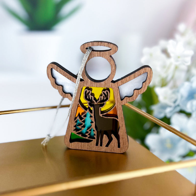 The Autumn Deer Ornament by Forged Flare® is a 3.5" Mother's Angels® figurine, featuring an angel-shaped silhouette with a deer, pine trees, and sunset scene—perfect as a unique gift for deer hunters or nature lovers.