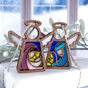 The Forged Flare® Christmas Nativity 2-Piece Bundle features 3.5" Mother's Angels® Mary and Joseph figurines displayed on a white gift box, with snow-covered branches and frosted windows in the background.