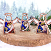 The Forged Flare® Christmas Nativity 3-Piece Bundle features Mother's Angels® 3.5" (H) angel figurines representing the Three Wise Men, displayed on a round wooden stand, evoking a charming and peaceful holiday scene.