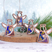 The Forged Flare® Christmas Nativity 4-Piece Bundle features 3.5" Mother's Angels® figurines of the Three Wise Men and Shepherd, each with colorful stained-glass insets, displayed against snowy pine branches on a wooden slab.