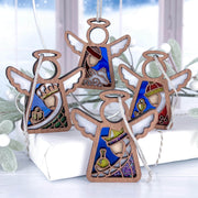 The Forged Flare® Christmas Nativity 4-Piece Bundle features 3.5" Mother's Angels® figurines of the Three Wise Men and a Shepherd, each with stained glass-style accents, displayed with a snowy window and festive white gift.