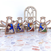 The Forged Flare® Christmas Nativity 4-piece bundle features 3.5" stained-glass style Mother's Angels® figurines—Three Wise Men and a Shepherd—displayed on terrazzo with a decorative arched window in the background.
