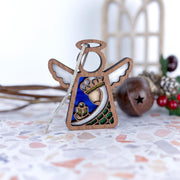 The Forged Flare® Christmas Nativity Green Wise Man 3.5" Angel Figurine from the Mother's Angels® collection rests on a terrazzo surface, with holiday decorations softly blurred in the background.