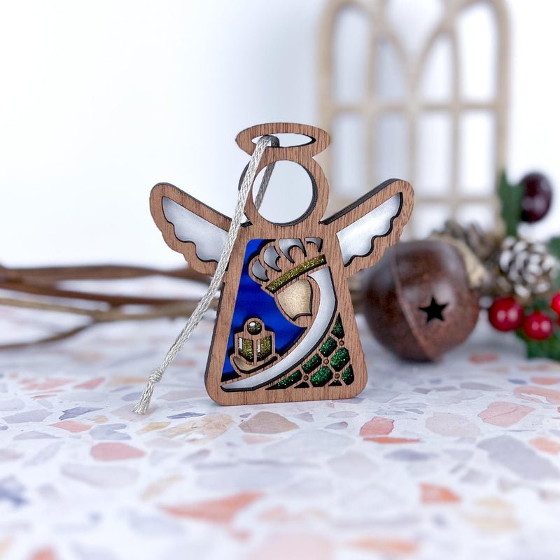 The Forged Flare® Christmas Nativity Green Wise Man 3.5" Angel Figurine from the Mother's Angels® collection rests on a terrazzo surface, with holiday decorations softly blurred in the background.