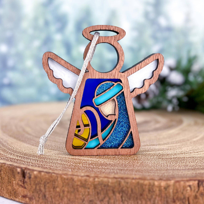 The Forged Flare® Christmas Nativity Joseph 3.5" Angel Figurine by Mother's Angels® features a stained glass-style scene with Mary and baby Jesus, white wings, halo, wood slice base, and glittery blue and yellow accents.