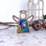 The Forged Flare® Mother's Angels® 3.5" Christmas Nativity Joseph angel figurine features white wings and a blue, yellow, and teal stained-glass-style scene of Mary holding baby Jesus—perfect for festive holiday décor.