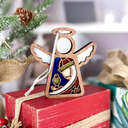 The Christmas Nativity Red Wise Man 3.5" Angel Figurine by Forged Flare® from the Mother's Angels® collection sits on a red gift box, surrounded by pine branches and burlap ribbon for a festive display.