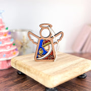 The Christmas Nativity Red Wise Man 3.5" Angel Figurine by Forged Flare® stands on a small riser with colorful details, set before a pink tree—perfect as a Mother's Angels® gift or festive Christmas ornament.