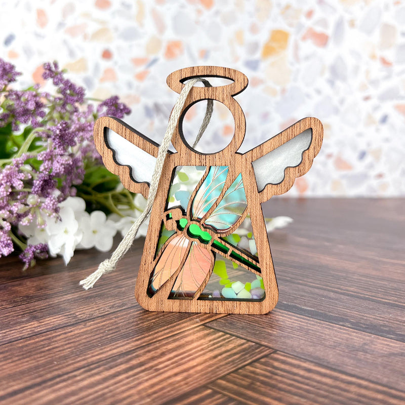 A Forged Flare® Warehouse Return - Dragonfly Ornament (Mother’s Angels® 3.5" Angel Figurine) with stained glass wings sits among purple and white flowers—a charming Amazon marketplace find.