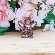The Monarch Butterfly Ornament with Imperfections by Forged Flare® is a 3.5" Mother's Angels® angel figurine, displayed on wood and surrounded by pink and white flowers—an ideal memorial gift to cherish special memories.