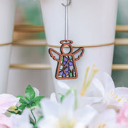A Forged Flare® Warehouse Return - Playful Purple Butterflies Ornament (3.5" H) Mother's Angels® figurine adds charm with stained glass wings—an eye-catching find among white vases, lilies, and lush green leaves for any Amazon shopper.