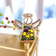 The Forged Flare® Pansy Ornament is a 3.5" (H) Mother's Angels® figurine with stained glass-style yellow and purple pansies, hanging from a white string—perfect for angel collections or as a Christmas tree ornament.