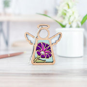 The Forged Flare® Purple Morning Glory Ornament | 3.5" (H) Angel Figurine from Mother's Angels® stands on a light wooden surface, with a white mug, green plant, and pencil softly blurred in the background.