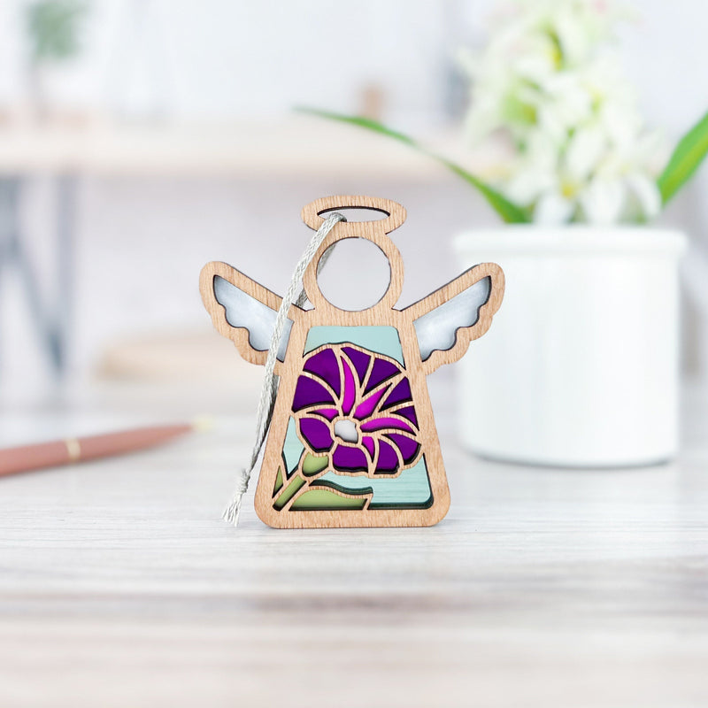 The Forged Flare® Purple Morning Glory Ornament | 3.5" (H) Angel Figurine from Mother's Angels® stands on a light wooden surface, with a white mug, green plant, and pencil softly blurred in the background.