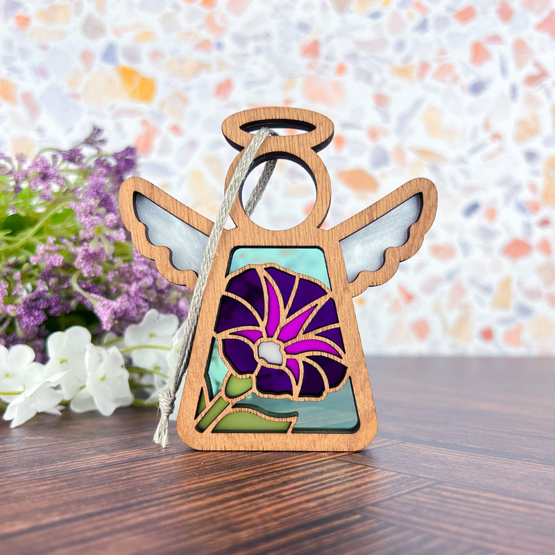 The Forged Flare® Purple Morning Glory Ornament | 3.5" (H) Mother's Angels® figurine features white wings and a hand-painted purple morning glory birth flower, displayed on wood surrounded by purple and white blooms, with a colorful mosaic background.