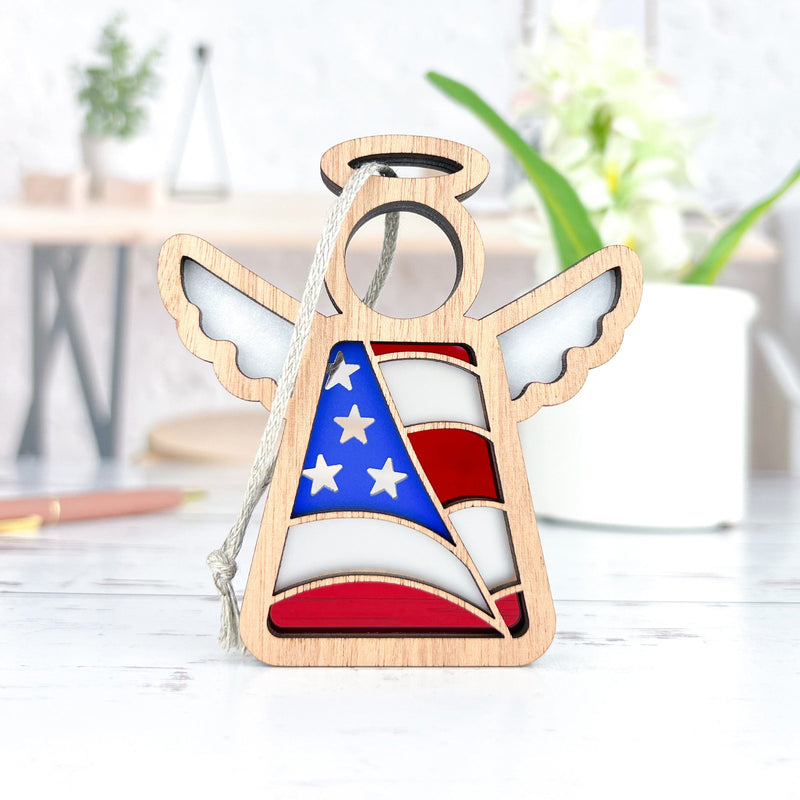 The Forged Flare® American Flag Ornament is a 3.5" Mother's Angels® figurine featuring a cut-out wooden angel design with an American flag pattern and hanging cord—an ideal patriotic gift for your decor.