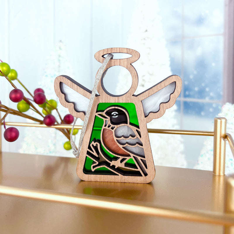 The Forged Flare® American Robin Ornament is a 3.5" stained glass angel figurine from Mother's Angels®, featuring green and white accents—an ideal bird lover gift, perfectly displayed among festive berries and wintry trees in the background.