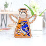 The Forged Flare® Blue Jay Ornament | 3.5" Mother's Angels® features a stained-glass style blue jay and pink flower—an ideal memorial or bird lover gift, beautifully displayed on a white table.
