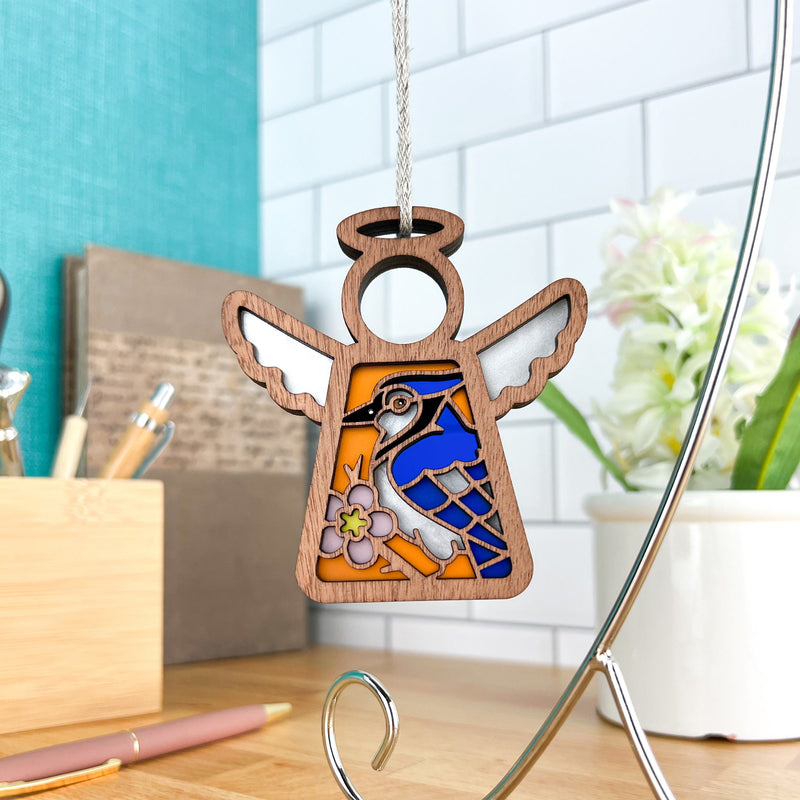 The Forged Flare® Blue Jay Ornament is a 3.5" angel figurine from Mother's Angels®, featuring stained-glass-style wings and a flower design—a thoughtful bird lover gift that's perfect for hanging as decor.