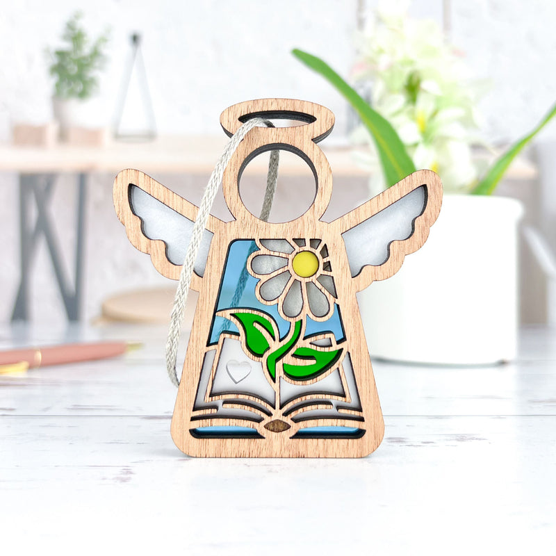 The Forged Flare® Book Lovers Ornament, a 3.5" Mother's Angels® figurine, features outstretched wings, a carved flower, an open book, and colorful stained glass—perfect as an author gift or thoughtful book club present.