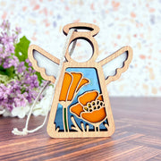 The California Poppy Ornament by Forged Flare® is a 3.5" angel figurine from the Mother's Angels® collection, featuring delicate wooden cut-outs adorned with vibrant California poppies on its body. The angel boasts simple white wings and a halo at the top, set against a background of blurred purple and white blossoms. This exquisite piece makes for a lovely Christmas ornament.