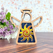 The Celestial Sun Ornament by Forged Flare® is a 3.5" wooden Mother's Angels® figurine with a glittery blue and sun design, twine hanger, and floral accents—ideal as a unique Christmas or beach gift.