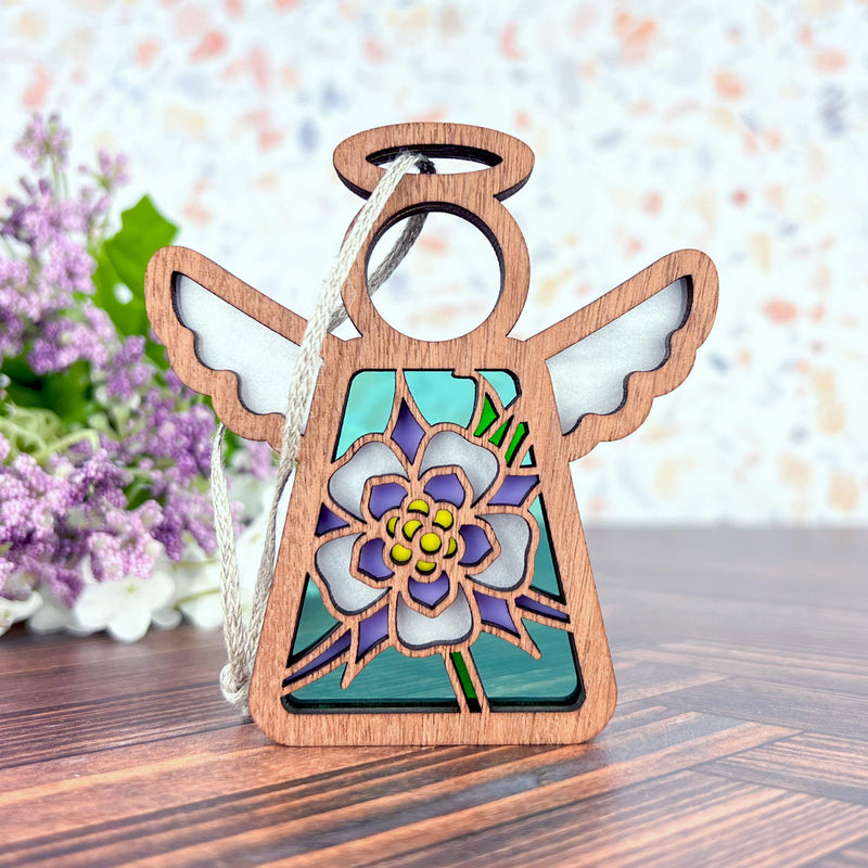 The Forged Flare® Columbine Ornament is a 3.5" Mother's Angels® figurine featuring white wings, a halo, and a stained-glass style Columbine flower design—ideal as a Christmas tree ornament or heartfelt gift.