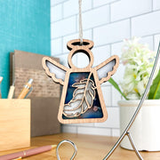 The Forged Flare® Feather Ornament | 3.5" (H) Angel Figurine from Mother's Angels® brings a mindful touch to any workspace—a beautiful gift or Christmas ornament, featuring a wooden angel with cut-out feather design.