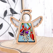 The Fuchsia Ornament by Forged Flare® is a 3.5" Mother's Angels® figurine with stained-glass style red and purple flowers, wings, halo, light wood base, and hanging cord—ideal as a Christmas ornament or unique flower gift.