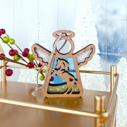 The Forged Flare® Horse Ornament | 3.5" (H) Angel Figurine from Mother's Angels® stands on a gold shelf, surrounded by horse decorations, red berries, and white Christmas trees against a snowy backdrop.