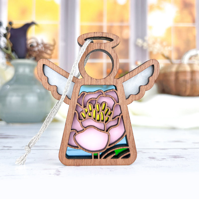 The Forged Flare® Pink Peony Ornament is a 3.5" wooden Mother's Angels® figurine with white wings and floral cutouts, perfect for your Christmas tree or indoor display. It stands out beautifully against home décor backgrounds.