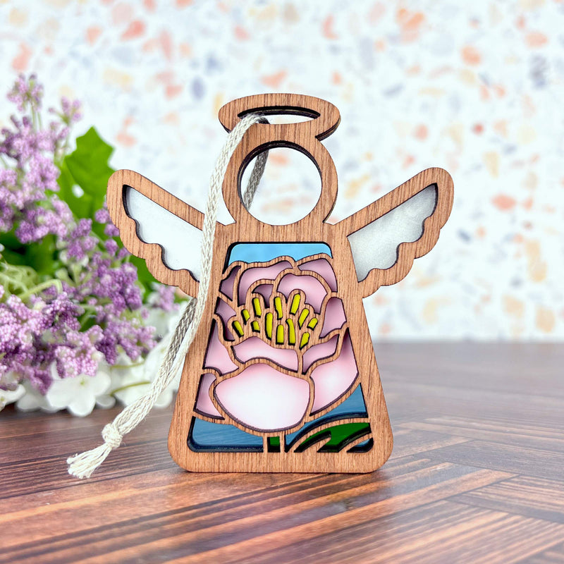 The Forged Flare® Pink Peony Ornament is a 3.5" Mother's Angels® wooden angel figurine with white wings, halo, tassel, and a stained-glass-style pink peony—perfect as a Christmas tree ornament or gift.
