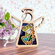 The Forged Flare® Red-Eyed Tree Frog Ornament is a 3.5" Mother's Angels® figurine with a stained-glass style frog panel—ideal as a unique gift or Christmas tree ornament. Displayed on wood, it’s perfect for frog lovers and collectors alike.